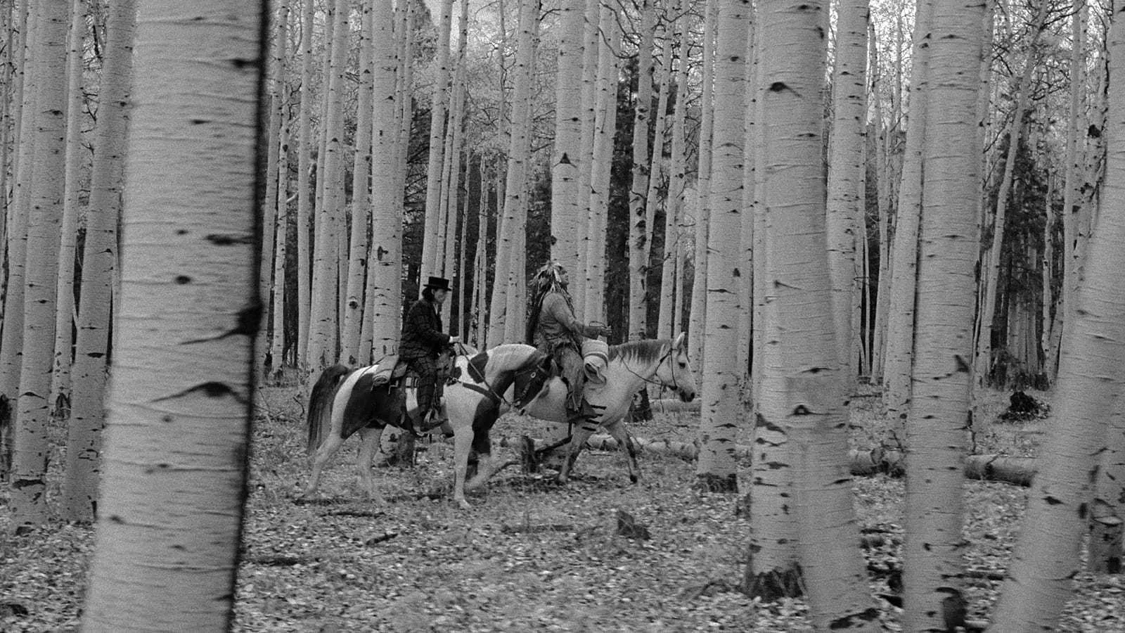 Scene from Dead Man — two riders on horseback moving through a birch forest