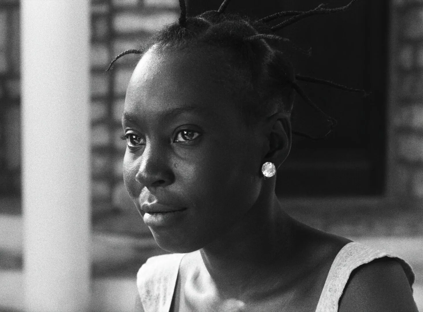 Close portrait of a young woman with braided hair and a crystal earring, her gaze soft and contemplative — a still from Black Girl (La Noire de..., 1966) by Ousmane Sembène