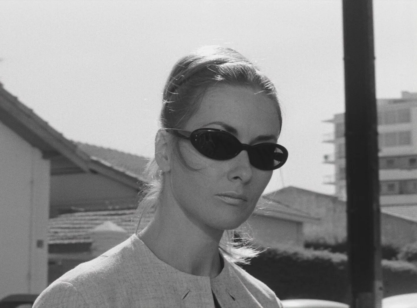 Portrait of a French woman in dark sunglasses on a sunlit street in Antibes — a still from Black Girl (La Noire de..., 1966) by Ousmane Sembène