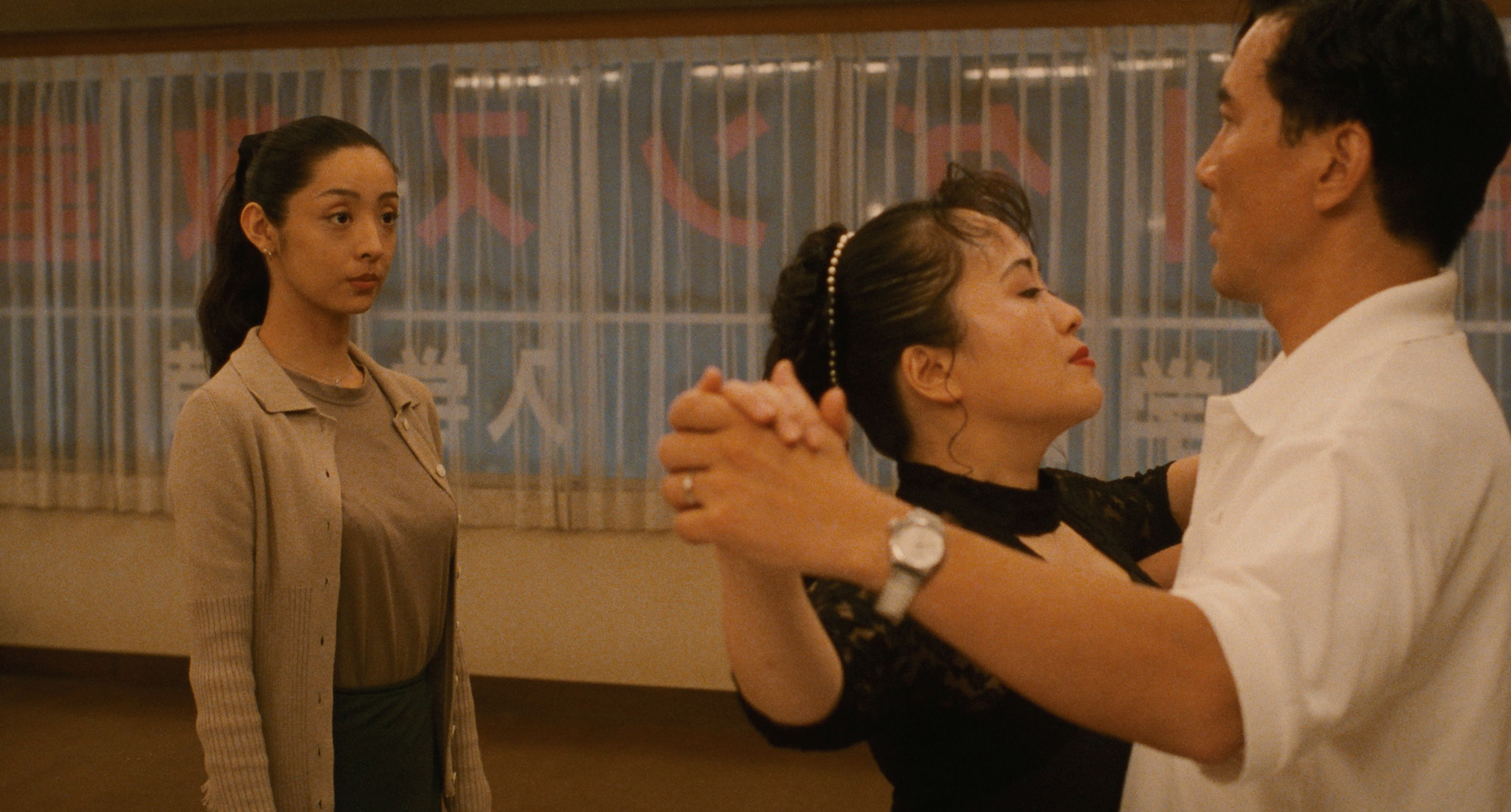 A young instructor watches a student practise with a partner in Shall We Dance? (1996)