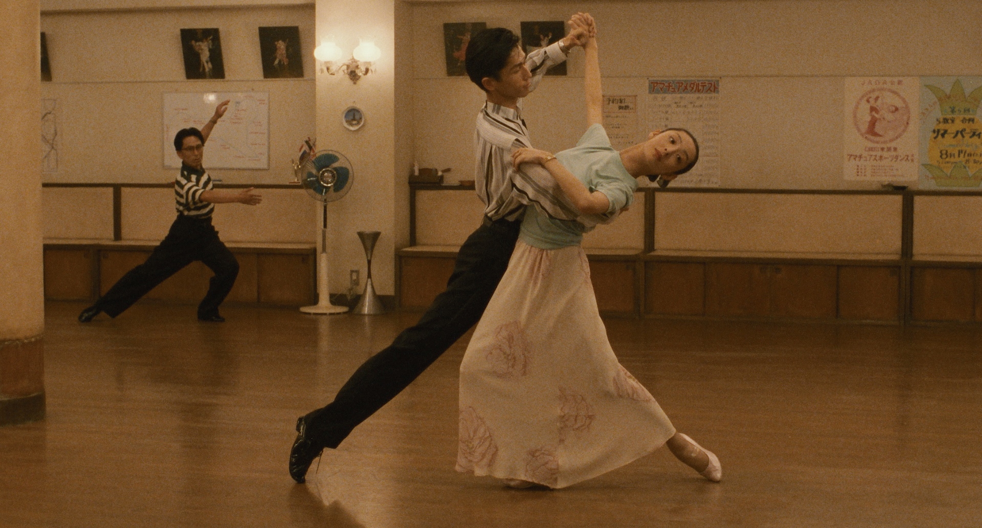A couple moves through an elegant ballroom figure in the practice room in Shall We Dance? (1996)
