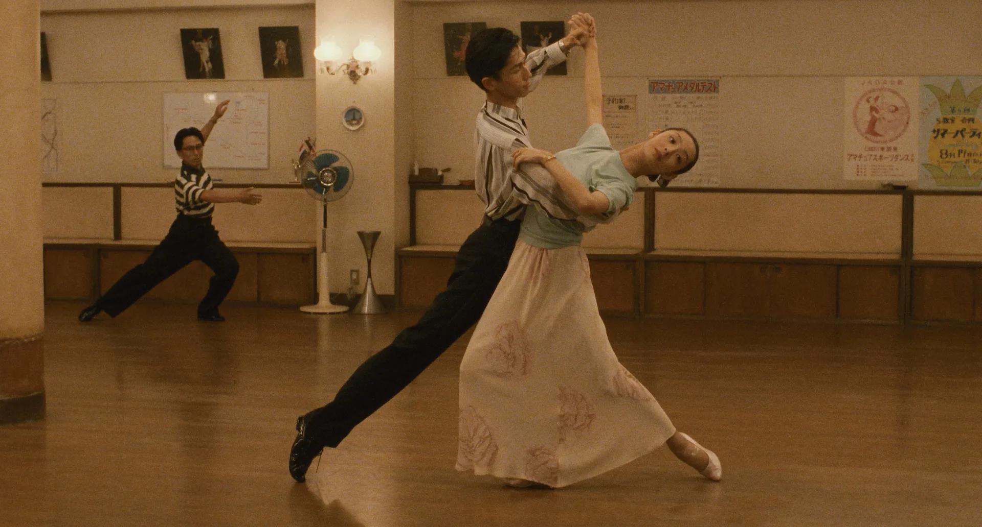 A couple moves through an elegant ballroom figure in the practice room in Shall We Dance? (1996)
