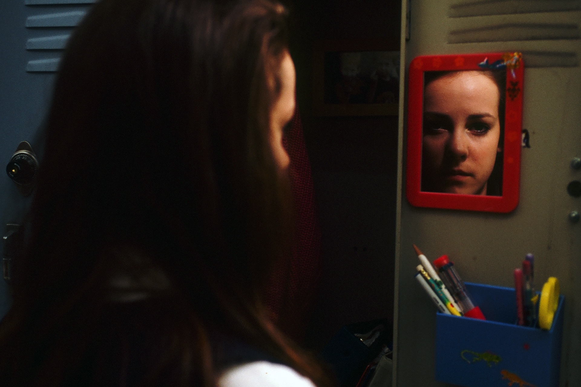 Jena Malone as Gretchen studies her reflection in a locker mirror in Donnie Darko (2001)