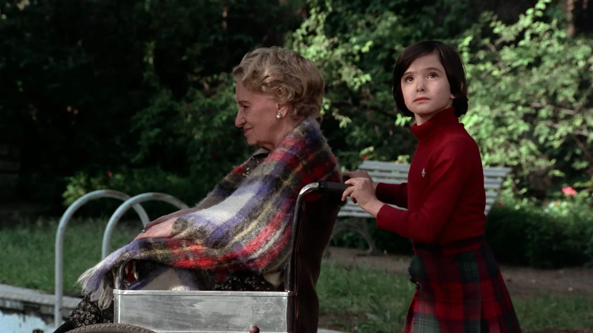 Ana pushes her mute grandmother's wheelchair through the overgrown garden in Cría Cuervos