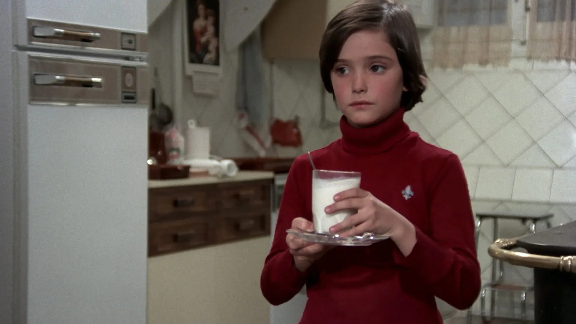 Ana Torrent holds a glass of milk in the family kitchen in Cría Cuervos