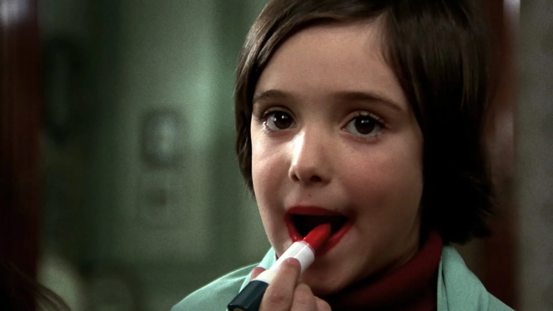 Young Ana applies red lipstick at a mirror in Cría Cuervos, Carlos Saura's 1976 classic