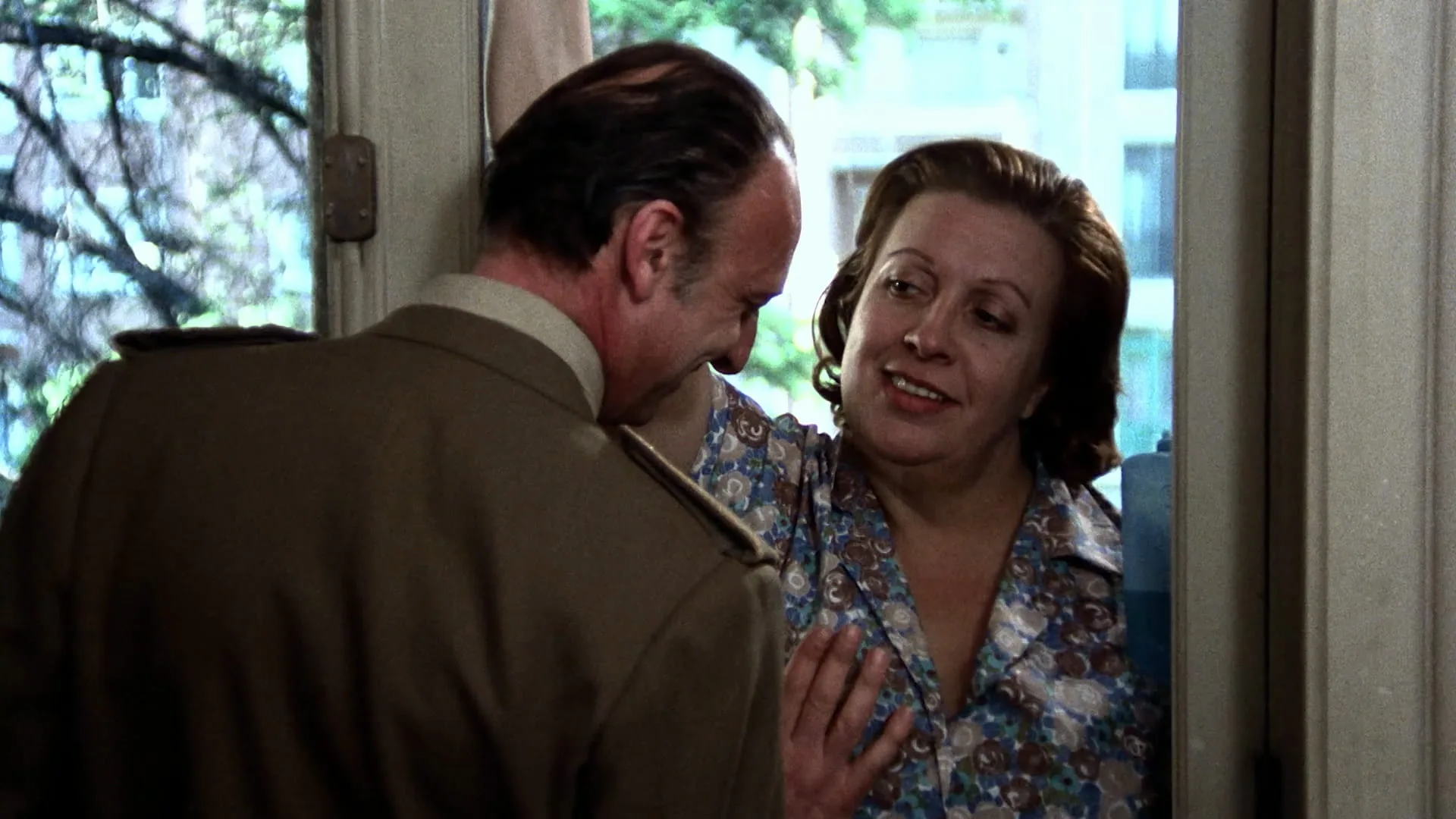 Ana's father Anselmo (Héctor Alterio) in military uniform with housekeeper Rosa (Florinda Chico) at a doorway in Cría Cuervos