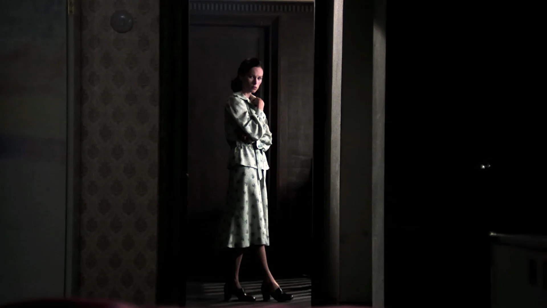 Ana's mother (Geraldine Chaplin) stands illuminated in a dark hallway in Cría Cuervos